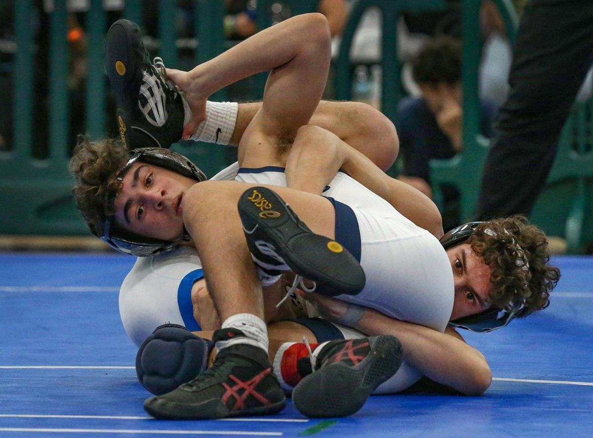 Christian Guzman of Christopher Columbus High School, at left, tangles with Adrian Morales, at the right, of South Dade High School during the GMAC Boys Wrestling Championship held at Ronald Reagan High School on Saturday, February 5, 2022.