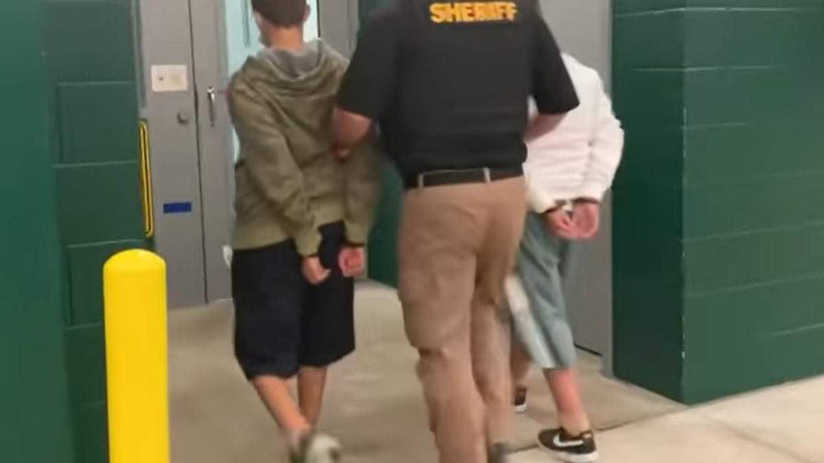 A screengrab from a Lee County Sheriff’s Office Facebook video. A Lee County, Florida, deputy leads two Harns Marsh Middle School students to jail on Sept. 9, 2021, after they were charged with conspiracy to commit a mass shooting.