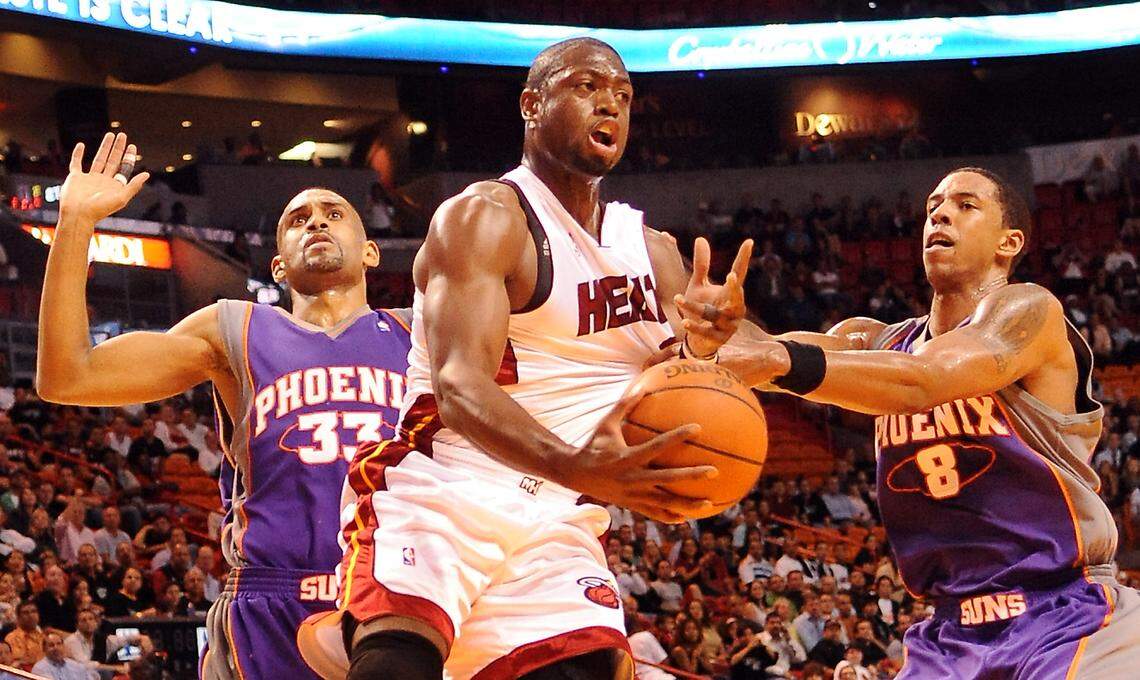 Miami Heat’s Dwyane Wade drives to the basket between Phoenix Suns’ Grant Hill, left, and Channing Frye at the American Airlines Arena in Miami Florida, Tuesday, November 3, 2009.