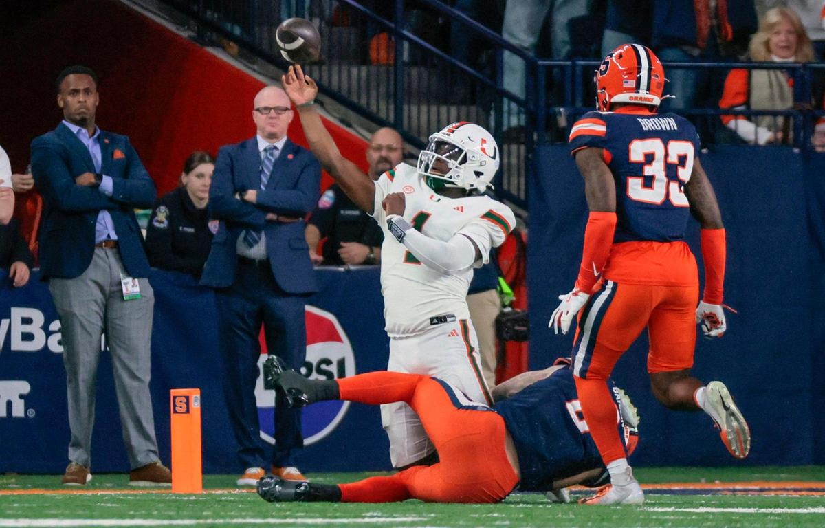 Miami Hurricanes quarterback Cam Ward (1) throws the ball as Syracuse Orange defensive back Justin Barron (8) pressures Ward for an incomplete pass in the second half of their NCAA football game in the JMA Wireless Dome at Syracuse University, Syracuse, New York on Saturday, November 30, 2024.