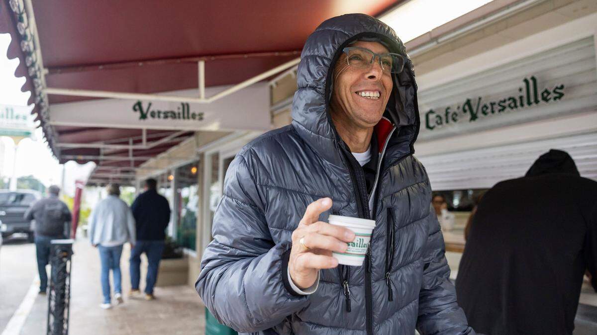 Andres Lozano leaves Versailles Restaurant Cuban Cuisine with his coffee as temperatures dip into the mid 40s across South Florida on Friday, Jan. 24, in Miami, Fla. Others may follow on Feb. 21 when temperatures are forecast to dip into the upper 50s.
