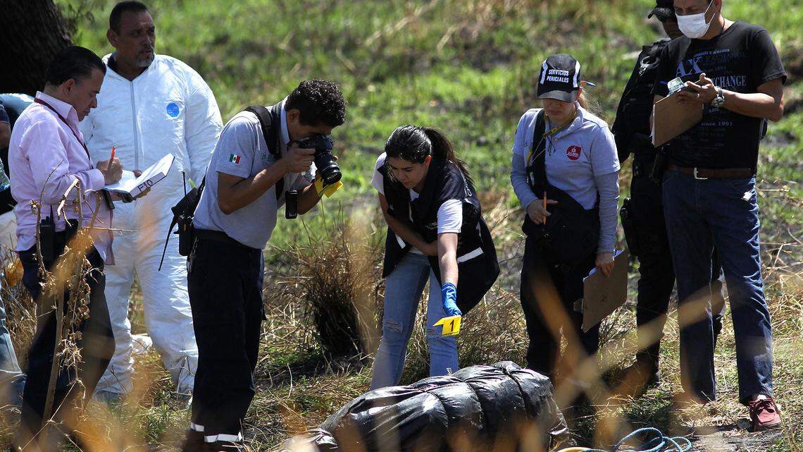 Forensic experts in Mexico work on the recovery of at least 10 bodies wrapped in bags found in a river channel.