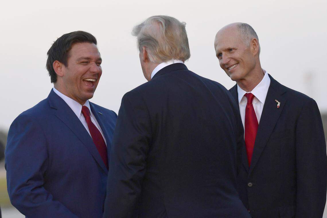 President Donald Trump talks with Republican candidate for governor Ron DeSantis, left, and Florida Gov. Rick Scott, right, after arriving on Air Force One at Southwest Florida International Airport in Fort Myers, Fla., Wednesday, Oct. 31, 2018.