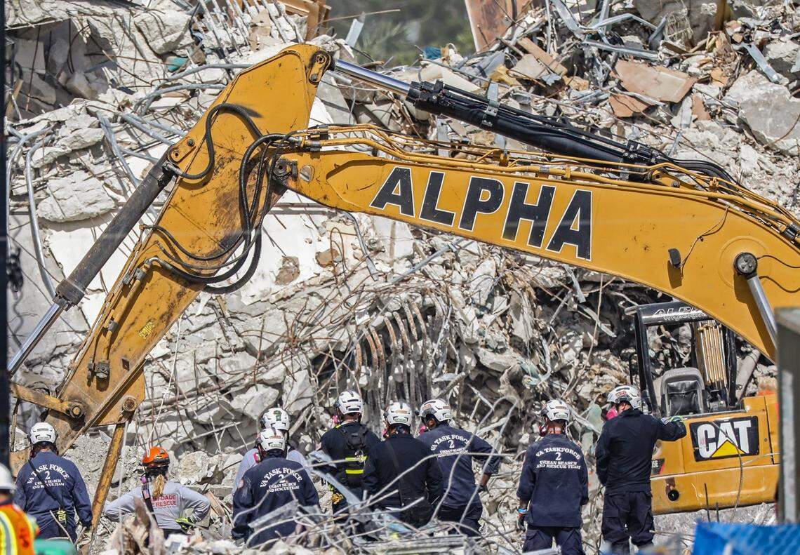 Search teams watch heavy machinery clear the debris field of the 12-story oceanfront condo, Champlain Towers South, in Surfside on Friday, July 9, 2021.