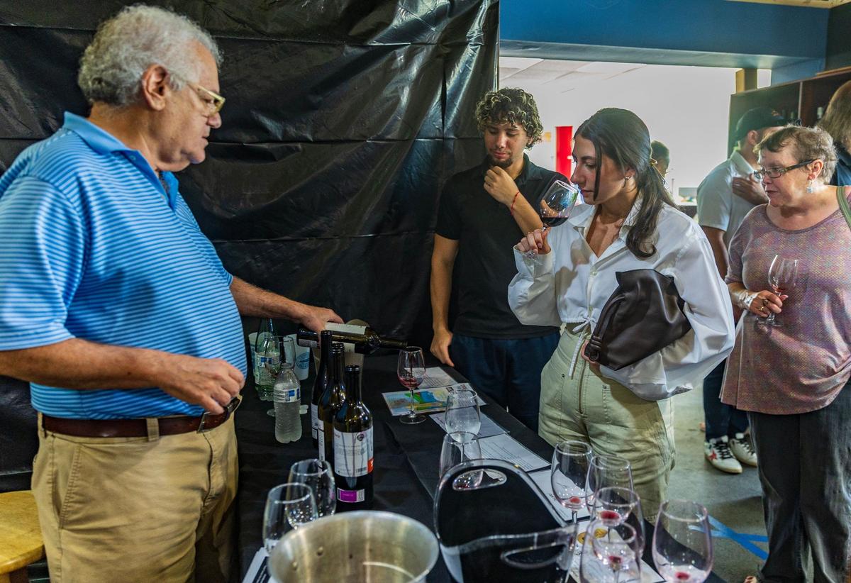 El antiguo propietario de Sunset Corners, Michael Bittel (izquierda), sirve un poco de vino a Frankie Pons y Karina Asturias (centro), durante una cata de vinos, en el emblemático negocio familiar Sunset Corners en 8701 Sunset Dr, en Miami, el sábado 1 de junio de 2024. Bittel se quedará para las catas de vino mientras el nuevo propietario Eddie Cruz se hace cargo del renovado Jensen's at Sunset Corners.