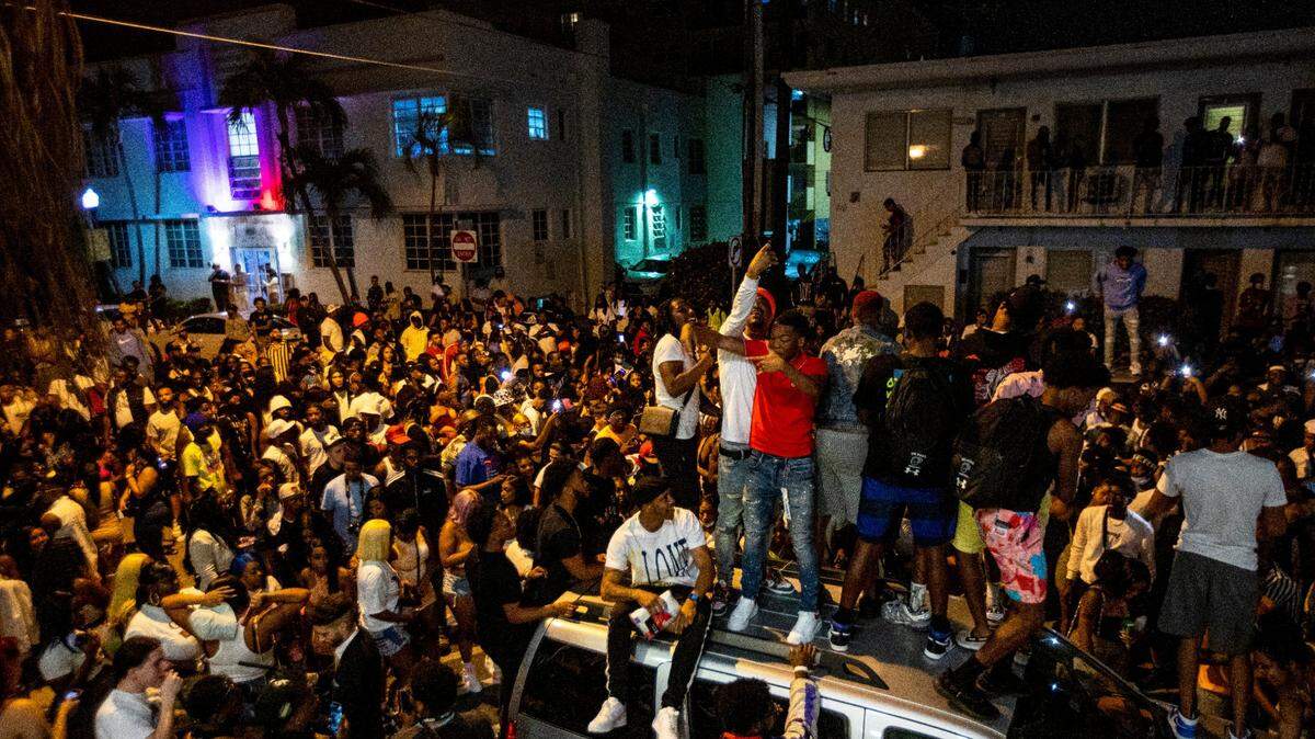 People stand on a car and fill the streets of a residential South Beach neighborhood during spring break in Miami Beach on Mar. 21, 2021.