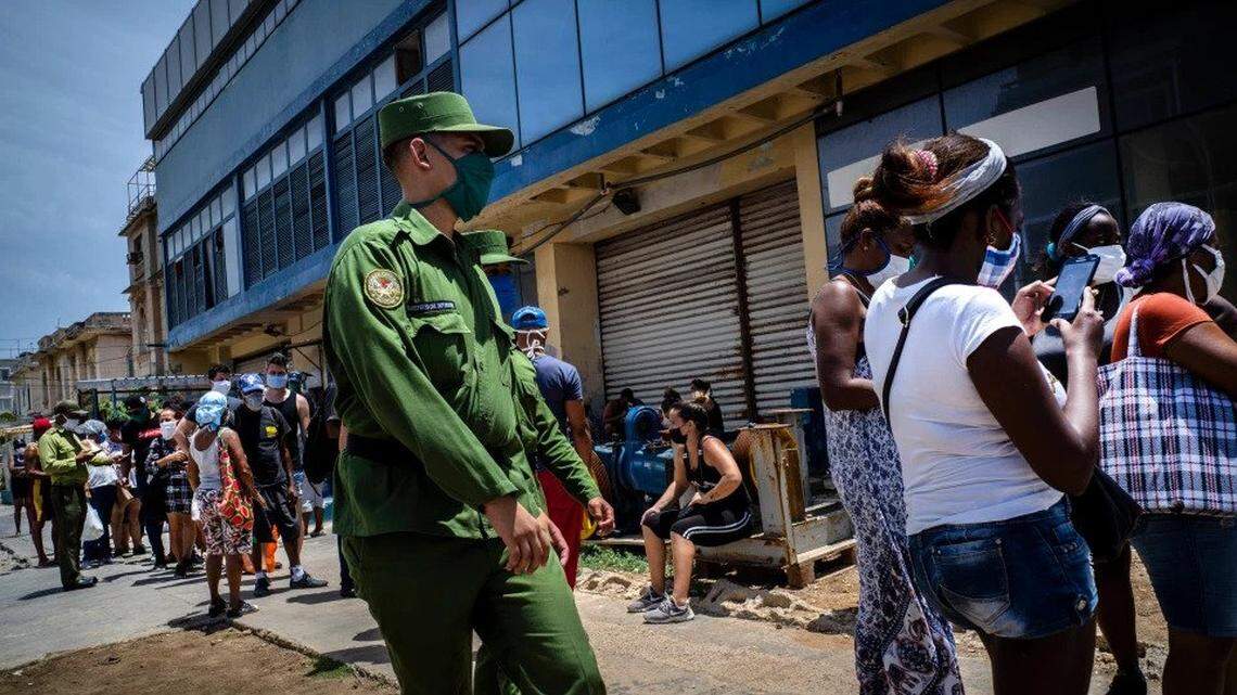To prevent hoarding during the pandemic, a soldier in Havana, Cuba, patrols outside a government-run food store where shoppers wait in line.