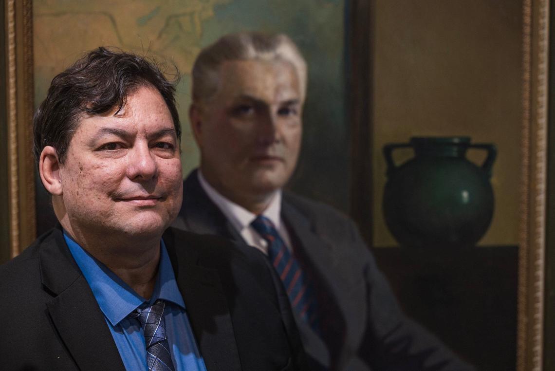 Elvis Fuentes, Executive Director of the Coral Gables Museum, posed next to a portrait at the museum of George Merrick, who planned and built the city of Coral Gables.