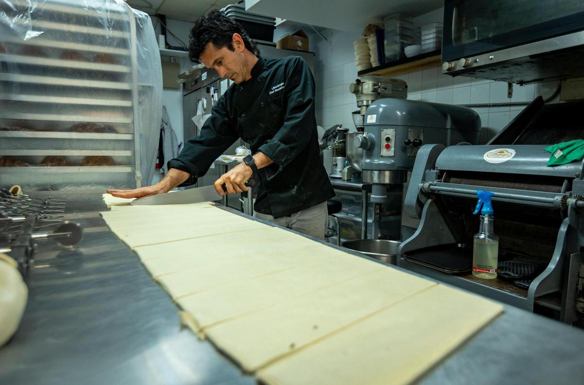 Yusel Montelongo cortando la masa en capas para hacer croissants en la cocina de L'Boulanger Maison du Croissant.