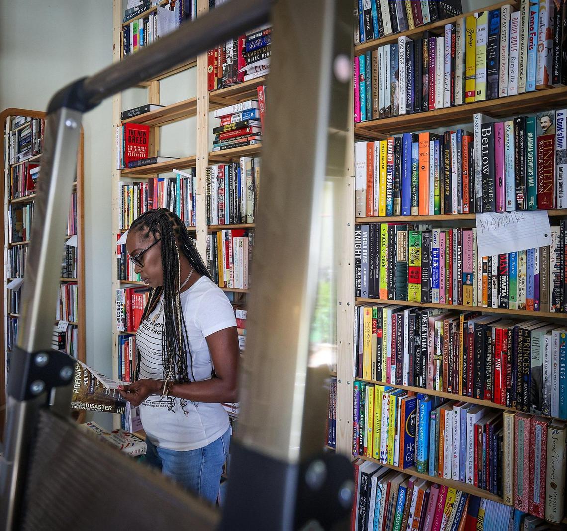 Sherina Jones, founder of Village Freedge and Pantry and co-owner of the Roots Bookstore and Marketplace sorts through books as the store prepares for its Juneteenth opening.