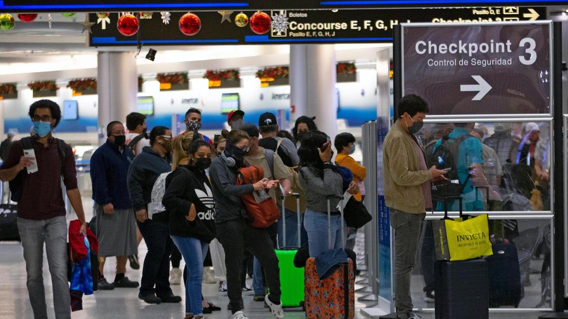 Travelers wearing protective face masks line up to pass through a security checkpoint at Concourse D at Miami International Airport on Monday, Dec. 28, 2020, in Miami, Florida. With the coronavirus surging out of control, the nation’s top public health agency pleaded with Americans not to travel and not to spend the holiday with people from outside their household.