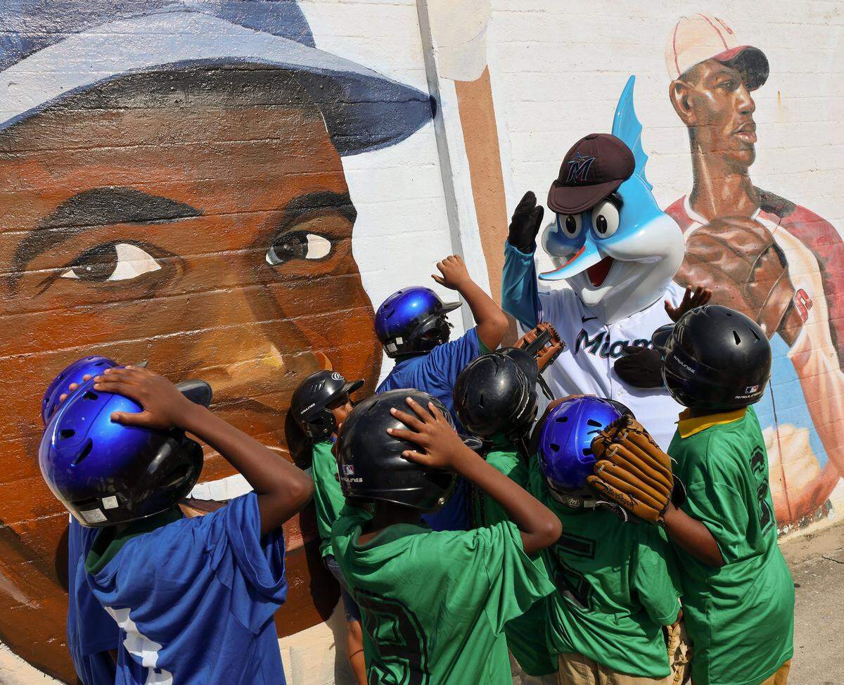Young baseball enthusiasts are greeted by the Miami Marlins mascot, “Billy,” at the renovated mural in Miami’s Dorsey Park that was vandalized in early June.
