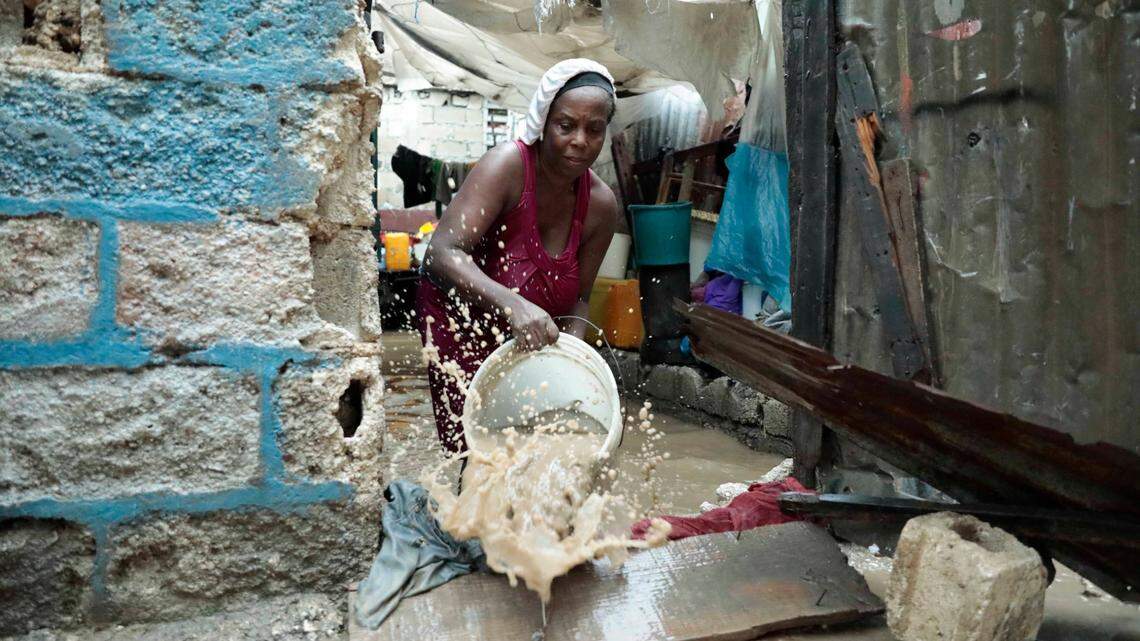 A woman uses a bucket to remove water from inside her flooded house, after a heavy rain in Port-au-Prince, Haiti, Saturday, June 3, 2023. (AP Photo/Odelyn Joseph)