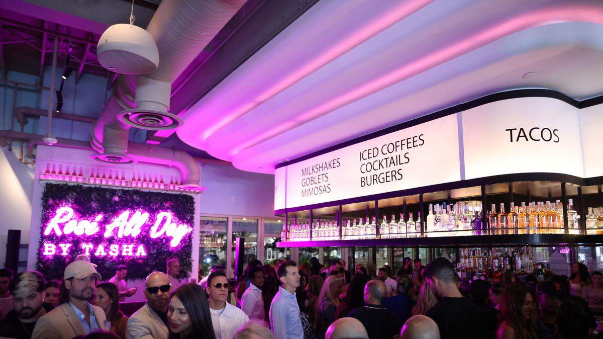 Guests at the grand opening of the Sugar Factory at the Firestone Garage mingle inside the restaurant.