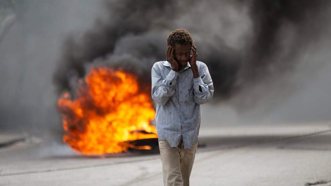 A man walks past a burning barricade during a protest over the death of journalist Romelson Vilcin in Port-au-Prince, Haiti, Sunday, Oct. 30, 2022.