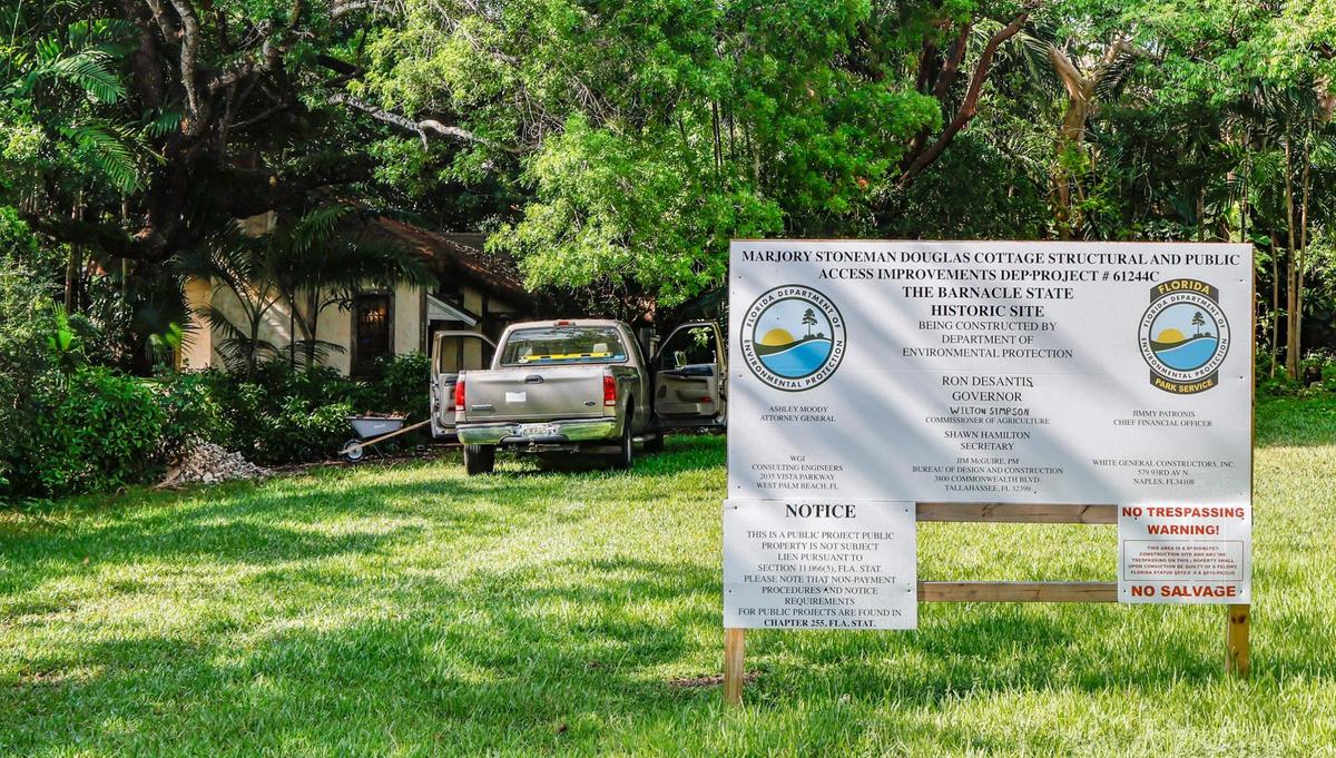 A contractor’s truck outside Marjory Stoneman Douglas cottage in Coconut Grove, where a sign posted by the state describes on-going restoration efforts. .