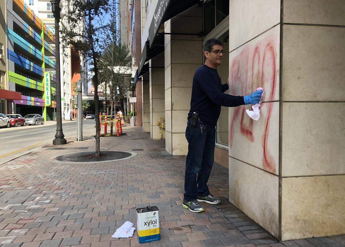 Angel Pena scrubs graffiti off a wall of the Vizcayne building on Northeast Second Street in downtown Miami on Sunday, May 31, 2020, the morning after demonstrations to protest the death of George Floyd turned violent.