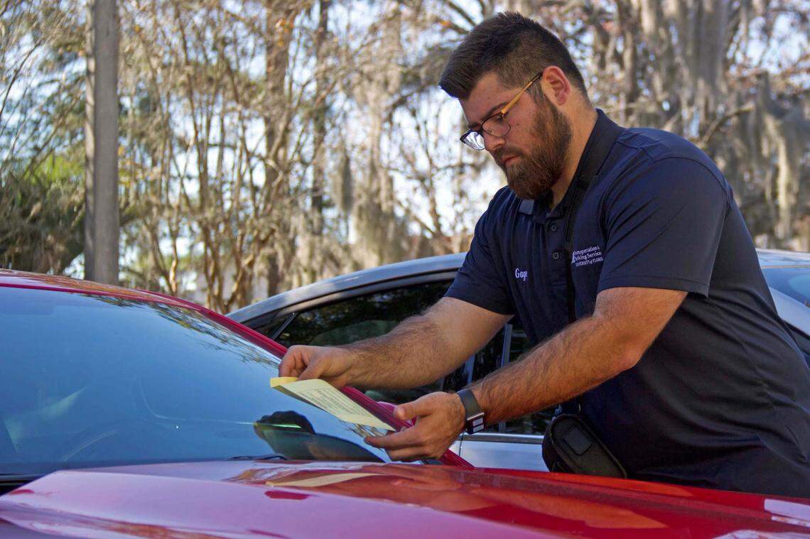 A University of Florida Transportation and Parking Services employee places a parking ticket on a vehicle at the University of Florida’s Gainesville campus on Jan. 18, 2022. (Kiara Cline/Fresh Take Florida)