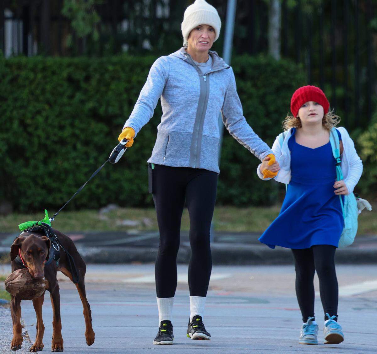 Hoodies, sweaters, coats, gloves, and knit hats is the attire for cool morning air as temperatures dropped due to arctic air on Tuesday, Nov. 11, 2025, in Miami, Florida. An unidentified woman walked a child to The Cushman School as her dog carried a coconut in its mouth.