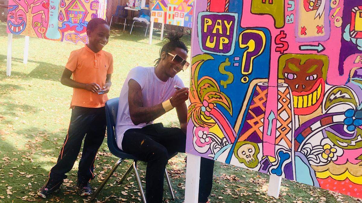 Artist Marcus Blake works with children on a climate change mural at the Motivational Edge in Allapattah.