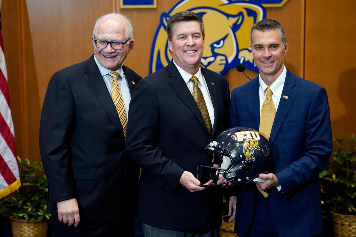 Florida International head football coach Mike MacIntyre, center, poses with president Mark Rosenberg, left, and athletic director Scott Carr, right, as he is introduced during a news conference at the university, Thursday, Dec. 9, 2021, in Miami. MacIntyre was most recently the defensive coordinator at Memphis. He replaces Butch Davis, the former Miami coach who parted ways with the school after going 24-32 over five seasons. (AP Photo/Lynne Sladky)