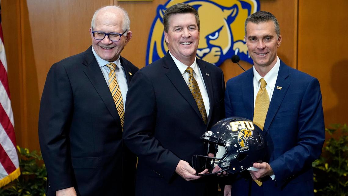 Florida International head football coach Mike MacIntyre, center, poses with president Mark Rosenberg, left, and athletic director Scott Carr, right, as he is introduced during a news conference at the university, Thursday, Dec. 9, 2021, in Miami. MacIntyre was most recently the defensive coordinator at Memphis. He replaces Butch Davis, the former Miami coach who parted ways with the school after going 24-32 over five seasons. (AP Photo/Lynne Sladky)