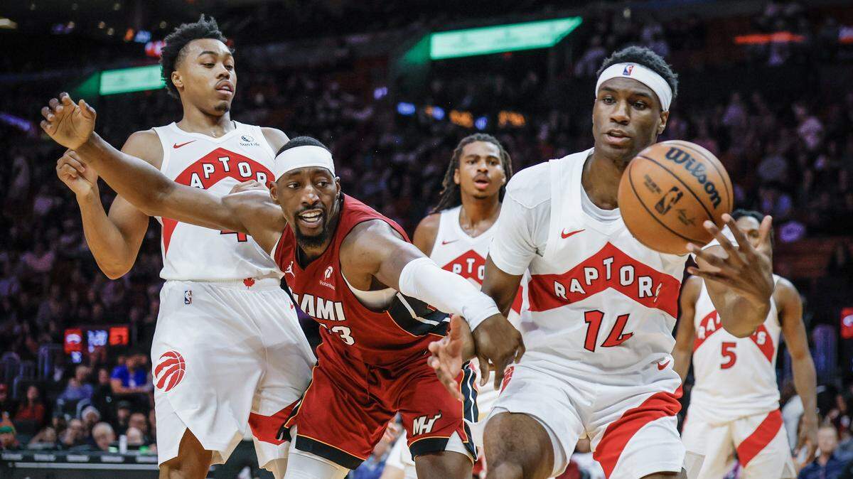 Miami Heat center Bam Adebayo (13) loses a rebound as Toronto Raptors guard Ja'Kobe Walter (14) grabs the ball under the basket during the second half of their NBA basketball game at the Kaseya Center in Miami, Florida, on Tuesday, December 23, 2025. 