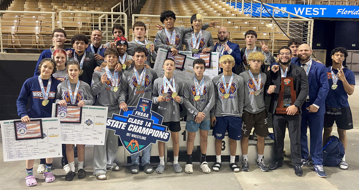 Mater Lakes wrestlers and coaches gather on the medal stand with the FHSAA Class 1A boys wrestling state championship trophy on Saturday at Silver Spurs Arena in Kissimmee.