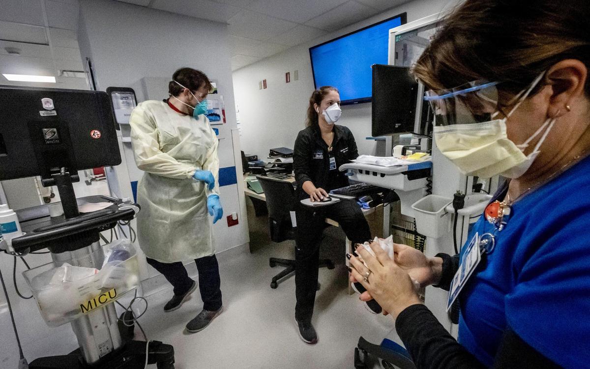  Nurse Alix Zacharski, right, sanitizes her hands as other doctors and nurses care for patients in the Medical Intensive Care Unit for COVID-19 patients at Jackson Memorial Hospital on July 23. Jackson is seeing COVID patients who are younger, healthier and sicker, which Zacharski said, is “scarier.”