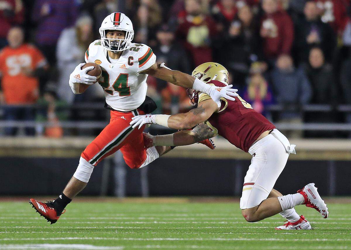 Miami Hurricanes running back Travis Homer (24) runs for a first down in the first quarter as the University of Miami plays Boston College at Alumni Stadium in Chestnut Hill on Friday, October 26, 2018.