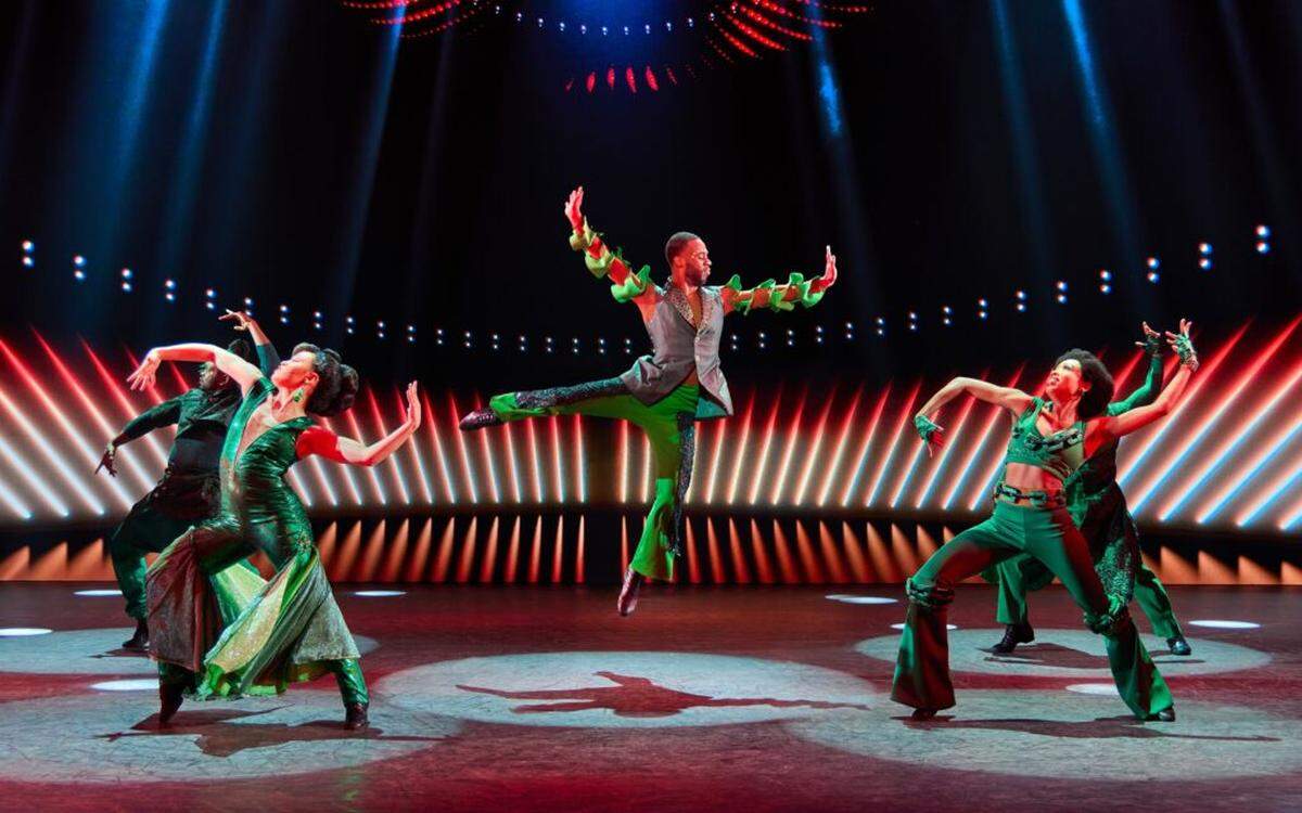 Dillard High School graduate Kameren Whigham, center, performs with the ensemble in the Emerald City scene in “The Wiz.”