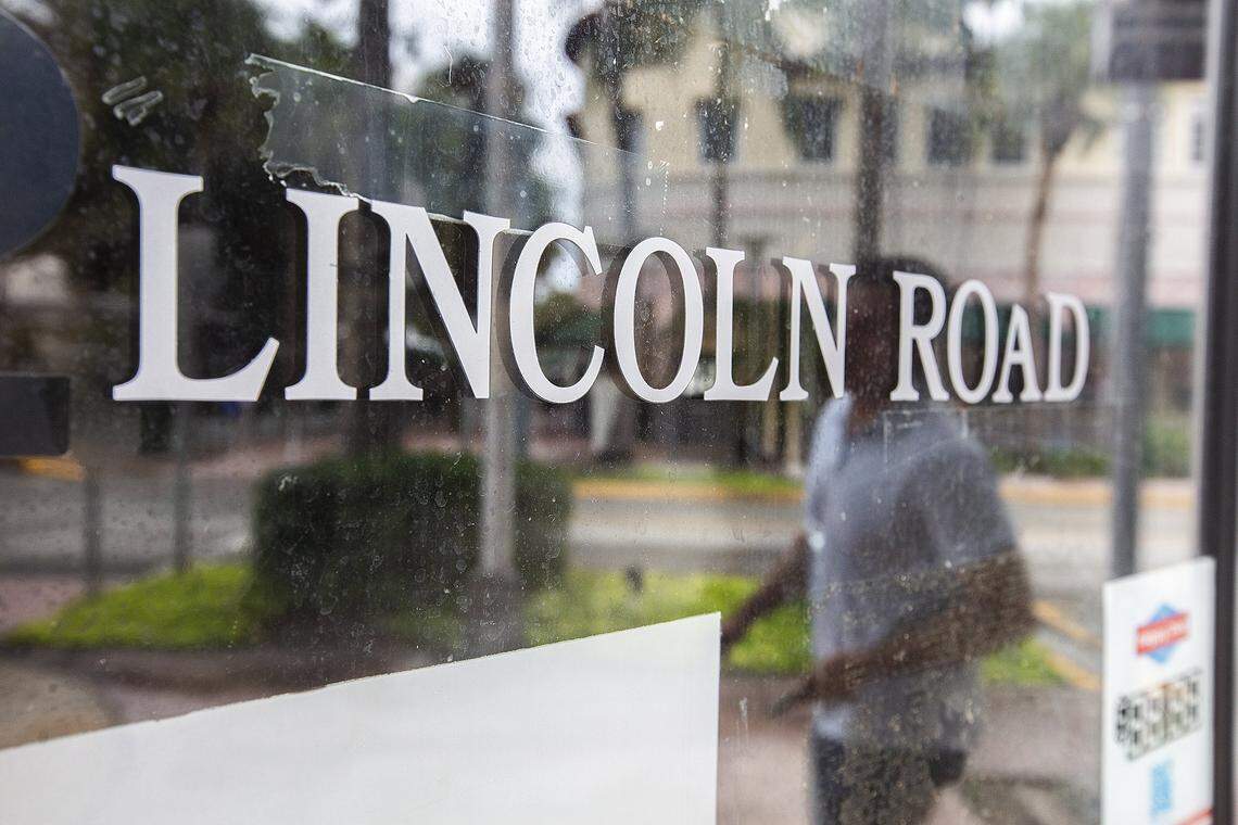 A man walking along Miami Beach’s Lincoln Road Mall is reflected in the window of a vacant shop.