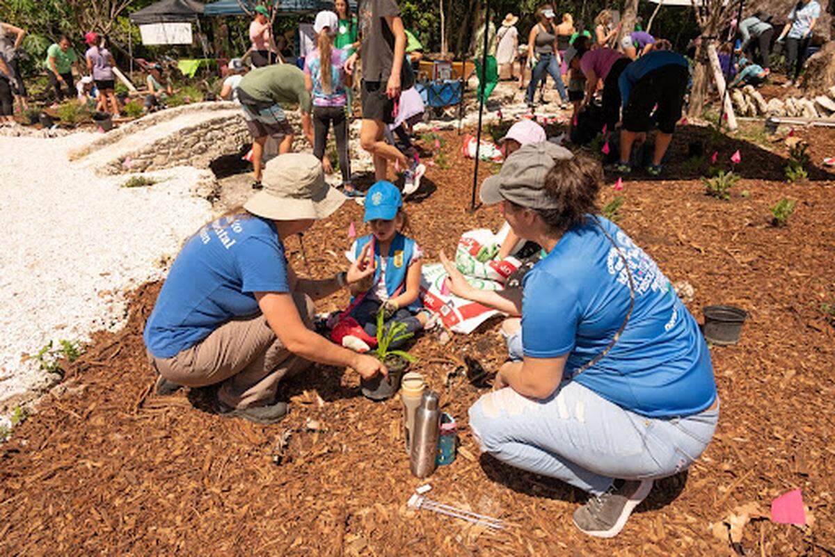 Citizens for a Better South Florida CEO Britany Ziems and program director Marina Barrientos with plant a tree with a girl scout.