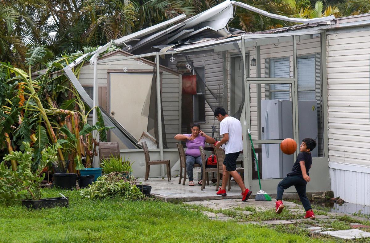 Young boys play near the damaged screen porch as the residents of Sunshine Village survey the damage and removed debris after a tornado touch ground at the mobile home park. A tornado possibly spawned by Hurricane Ian caused downed trees, traffic lights, and damage to property in and around Sunshine Village, a mobile home park in Davie, Florida on Wednesday, September 28, 2022.