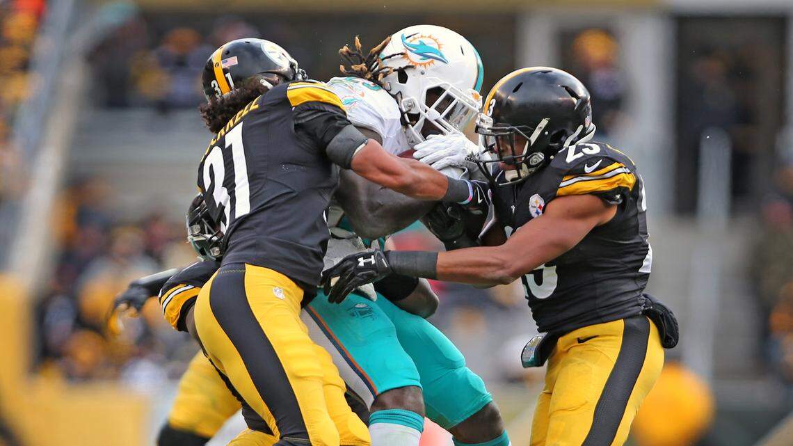  Miami Dolphins Jay Ajayi is tackled by Pittsburgh Steelers Ross Cockrell 31, and Mike Mitchell 23, in the second quarter in the NFL Wild-Card Playoffs at Heinz Stadium, Pittsburgh, PA, January 8, 2017.