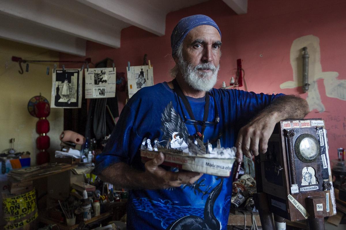 Jorge Alberto Hernandez Cadi, a Cuban outsider artist who lives in Alamar, holds a boat he has created from paper and old photographs. Hernandez is known as “El Buzo” (the diver) because he scavenges through the trash to find objects for his art.