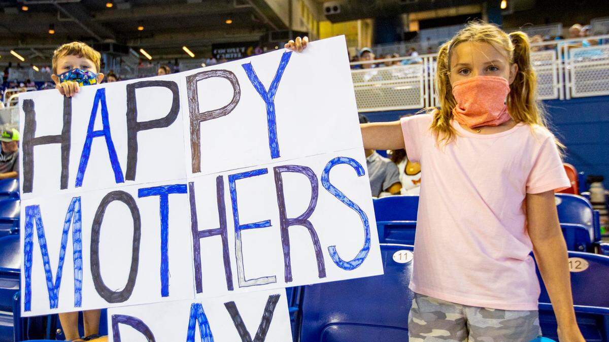 Brother and sister Hayes, 4, left, and Sutton, 9, right, hold a ‘Happy Mother’s Day’ sign while watching the Miami Marlins play last season at loanDepot park in Little Havana.