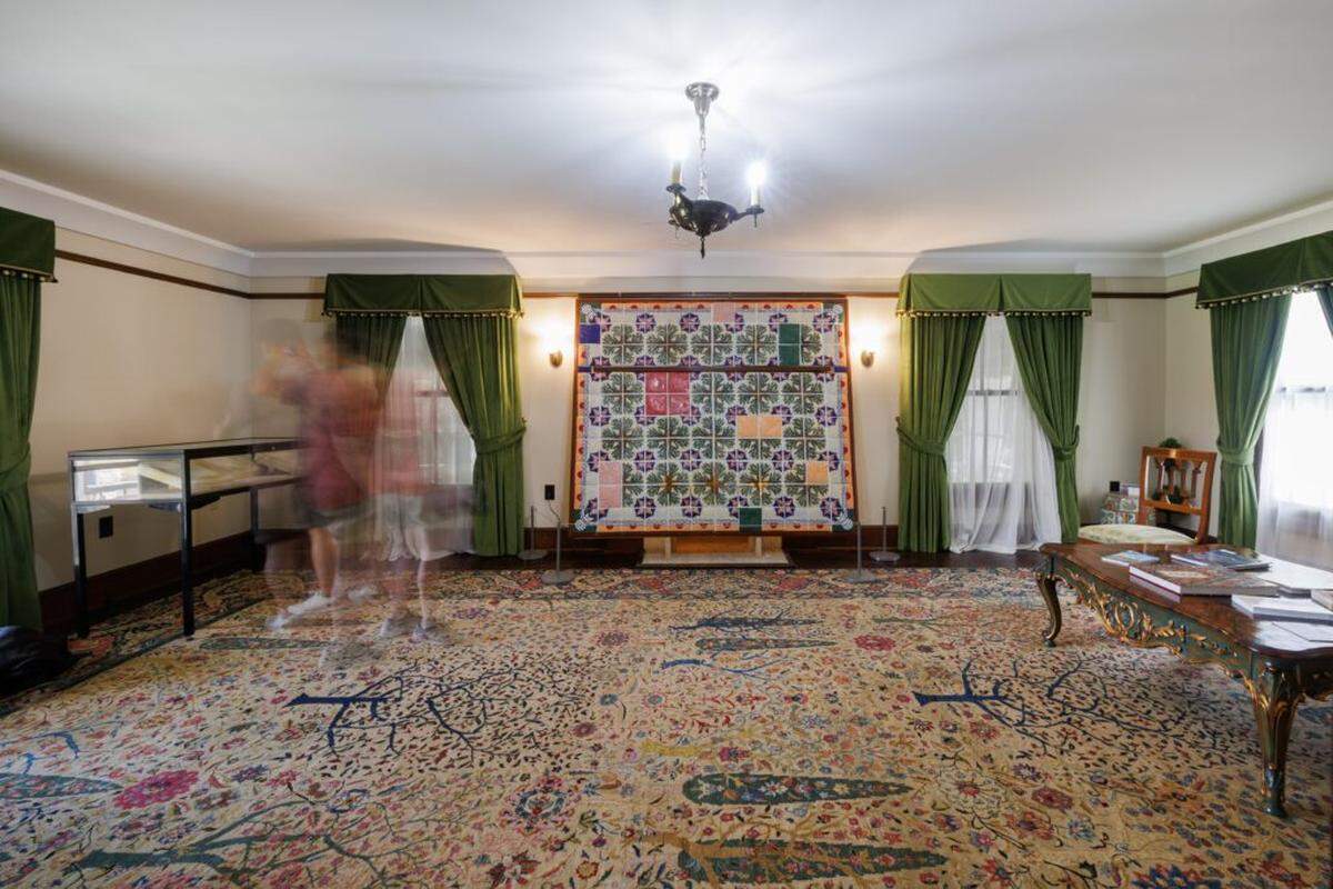 A view of the “Deering Tiles” installation shows the other components of the exhibition, which include a case containing the plaster molds used to pour the porcelain slip for the tiles and reference books used in creating the tiles.