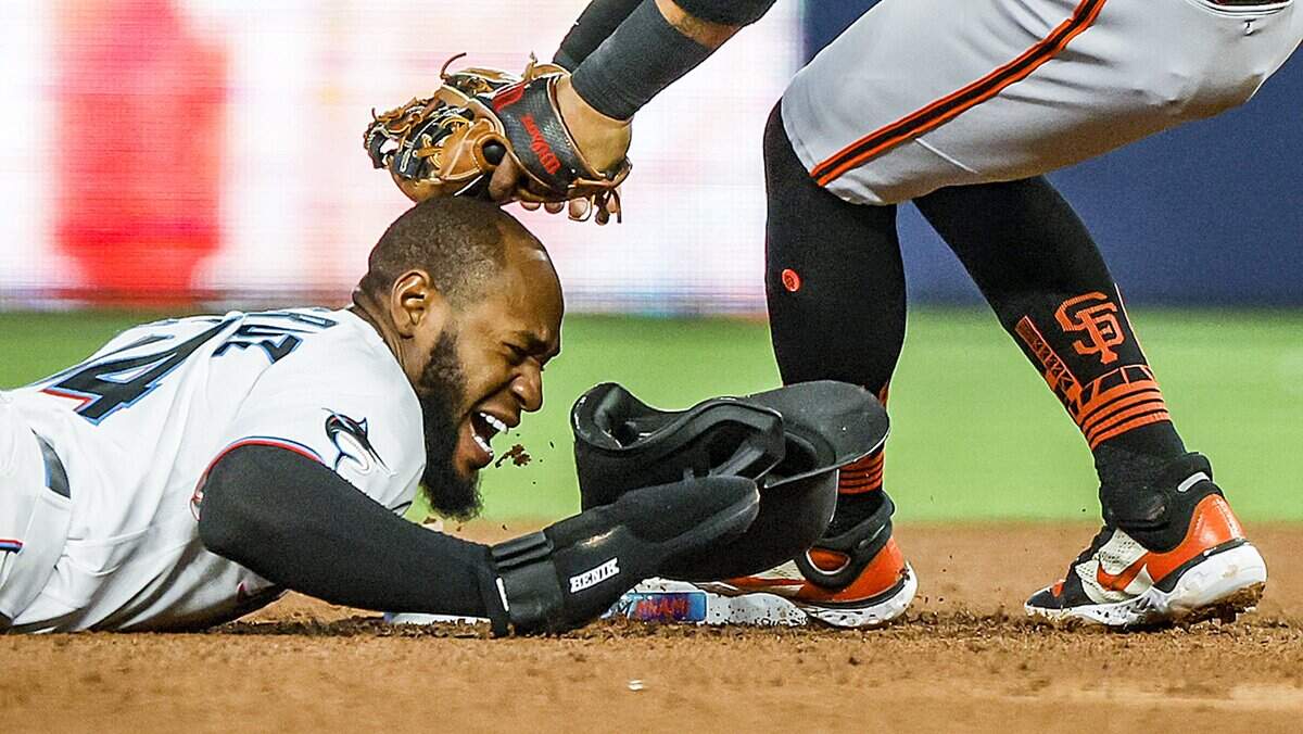 Miami Marlins left fielder Bryan De La Cruz (14) is tapped in the head by San Francisco Giants second baseman Thairo Estrada (39) as De La Cruz slides safely into second base in the fourth inning at LoanDepot Park in Miami, Florida, on Wednesday, April 19, 2023.