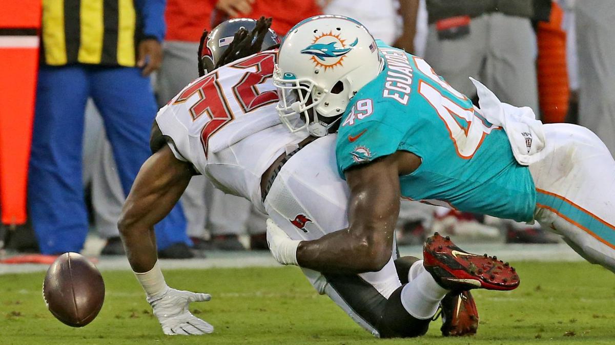 Miami Dolphins linebacker Sam Eguavoen (49) causes Tampa Bay Bucs Andre Ellington (32) to fumble the ball in the first quarter at Raymond James Stadium in Tampa, Florida, Friday, August, 16, 2019.