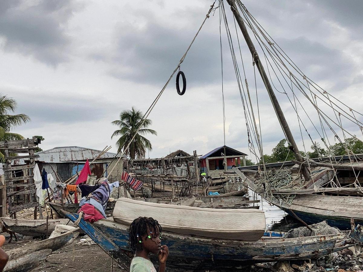 Boucan Noël, Haiti, August 19, 2021 - A young girl walks by old grounded boats in the town of Boucan Noël where many homes were destroyed or damaged by the earthquake on August 14, 2021.