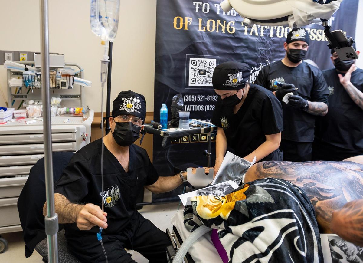 Dr. Steven Burns, 60, left, and R.N. Sofia Reichard Manrique, 25, monitor Dom Groenveld, who is anesthetized, as Sedation Ink artists work on a back tattoo at a surgical office on Monday, Jan. 20, 2025, in Miami, Fla. Sedation Ink offers tattooing under anesthesia, allowing clients to complete extensive body art in a single session.