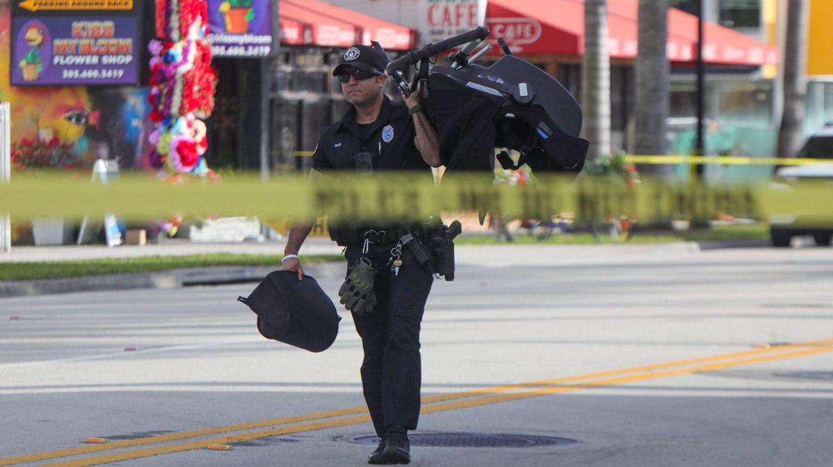 A Miami police officer carries a stroller on Biscayne Boulevard on Wednesday, Feb. 14, 2024, after a woman pushing a baby was killed in a crash hours earlier.