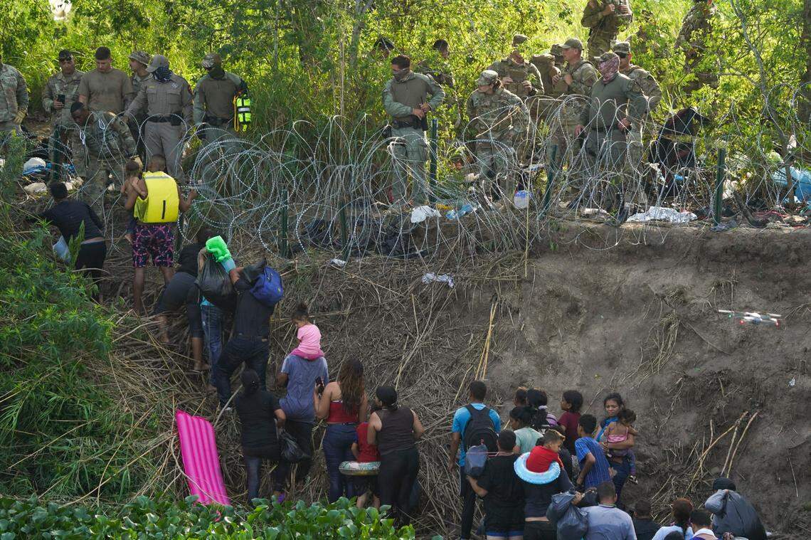 Texas state police finish placing barbed-wire as migrants walk up the bank of the Rio Grande river, seen from Matamoros, Mexico, Wednesday, May 10, 2023. The U.S on May 11 will begin denying asylum to migrants who show up at the U.S.-Mexico border without first applying online or seeking protection in a country they passed through, according to a new rule released May 10. (AP Photo/Fernando Llano)