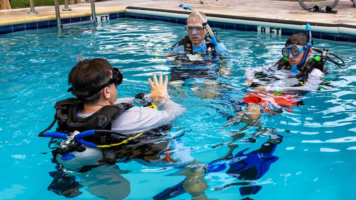 Diver’s Paradise dive instructor Michael Pondel, left, directs Paul Miller, center, and Matteo Miller, 12, right, during a pool session on Thursday, August 8, 2024, in Key Biscayne, Fla.