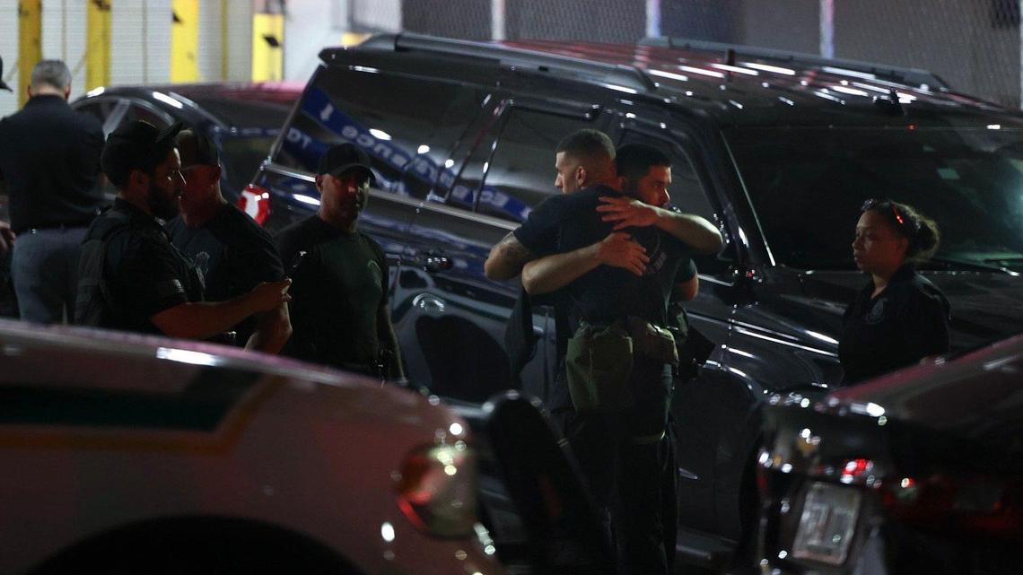 Police officers and other officials stand outside the Ryder Trauma Center after a Miami-Dade police officer was shot on Monday, Aug. 15, 2022.