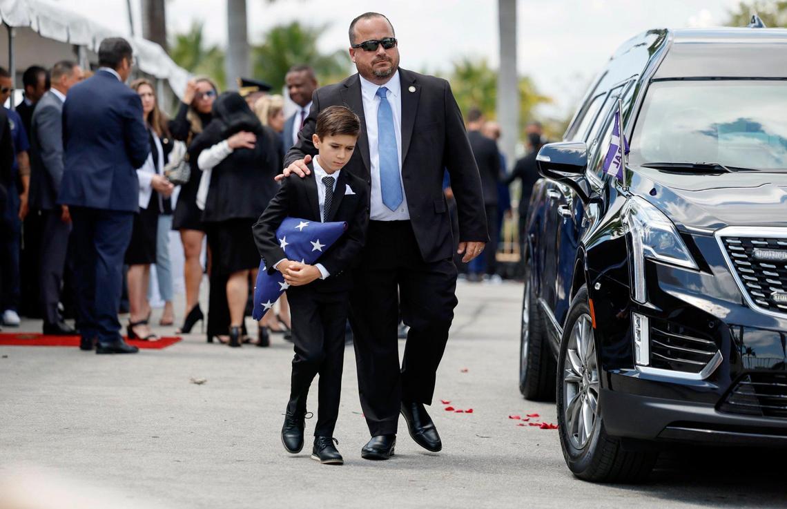 Esteban Ferreiro, chief of staff for Commissioner Manolo Reyes, walks with Matthew Reyes, the commissioner’s grandson, toward the awaiting hearse during a memorial service at Miami City Hall on Wednesday, April 16, 2025.