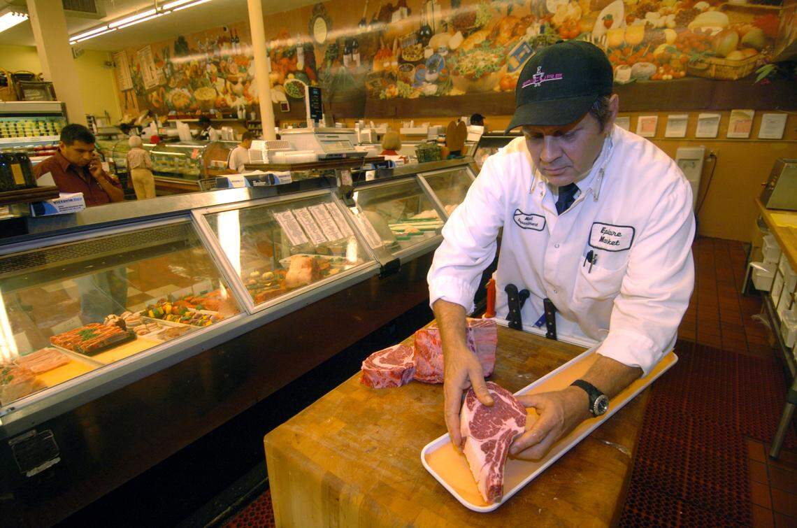 Rudiger Fersch, a butcher at Epicure, cuts a piece of beef on a butcher block for his customers.