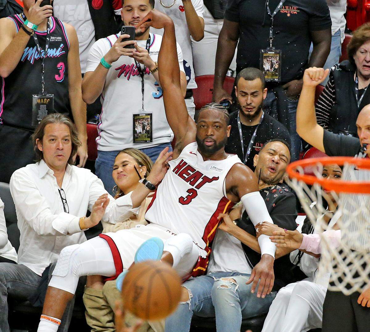 Miami Heat guard Dwyane Wade crushes singer John Legend and his wife Chrissy Teigen after Wade missed a basket in the fourth quarter as they play the Philadelphia 76ers at the AmericanAirlines Arena in Miami, Florida, Tuesday, April, 9, 2019.