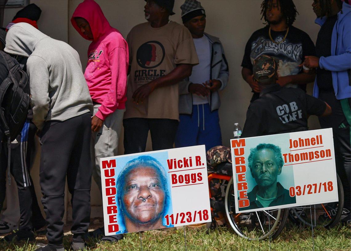 Young men gather with staff members of Circle of Brotherhood behind signs of those who were killed by gun violence at a rally to address a budget gap following the loss of federal funding.